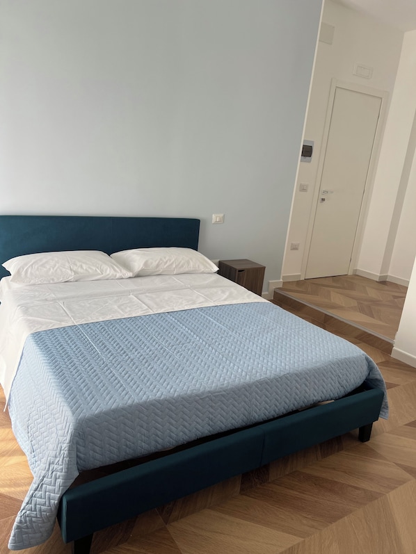 Un dormitorio con cama, mesita de noche y una puerta.