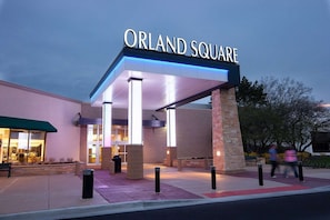 Ein Gebäudeeingang mit einem Schild, auf dem 'ORLAND SQUARE' steht, und einem überdachten Zugang.
