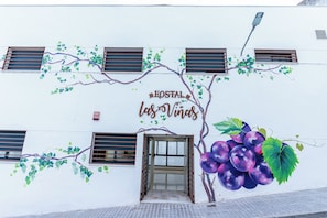 Un edificio con un letrero que dice 'Hostal las Vinas' e una gran ilustración de uvas.