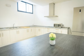 A kitchen with a dark countertop, a microwave, and a small potted plant.
