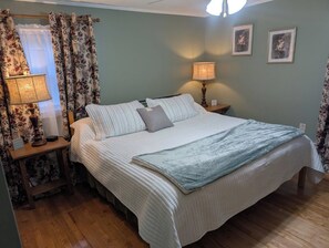Une chambre à coucher avec un lit, deux lampes de chevet, une table de chevet et une fenêtre avec des rideaux.