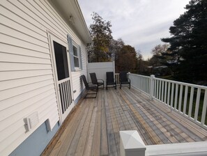 Une terrasse en bois avec une balustrade blanche, deux chaises et une petite table.
