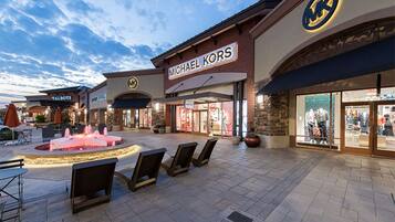 A shopping mall with a Michael Kors store, outdoor seating, and a fountain.