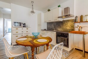 Una cocina moderna con armarios blancos, una isla central y un comedor con una mesa redonda y sillas.