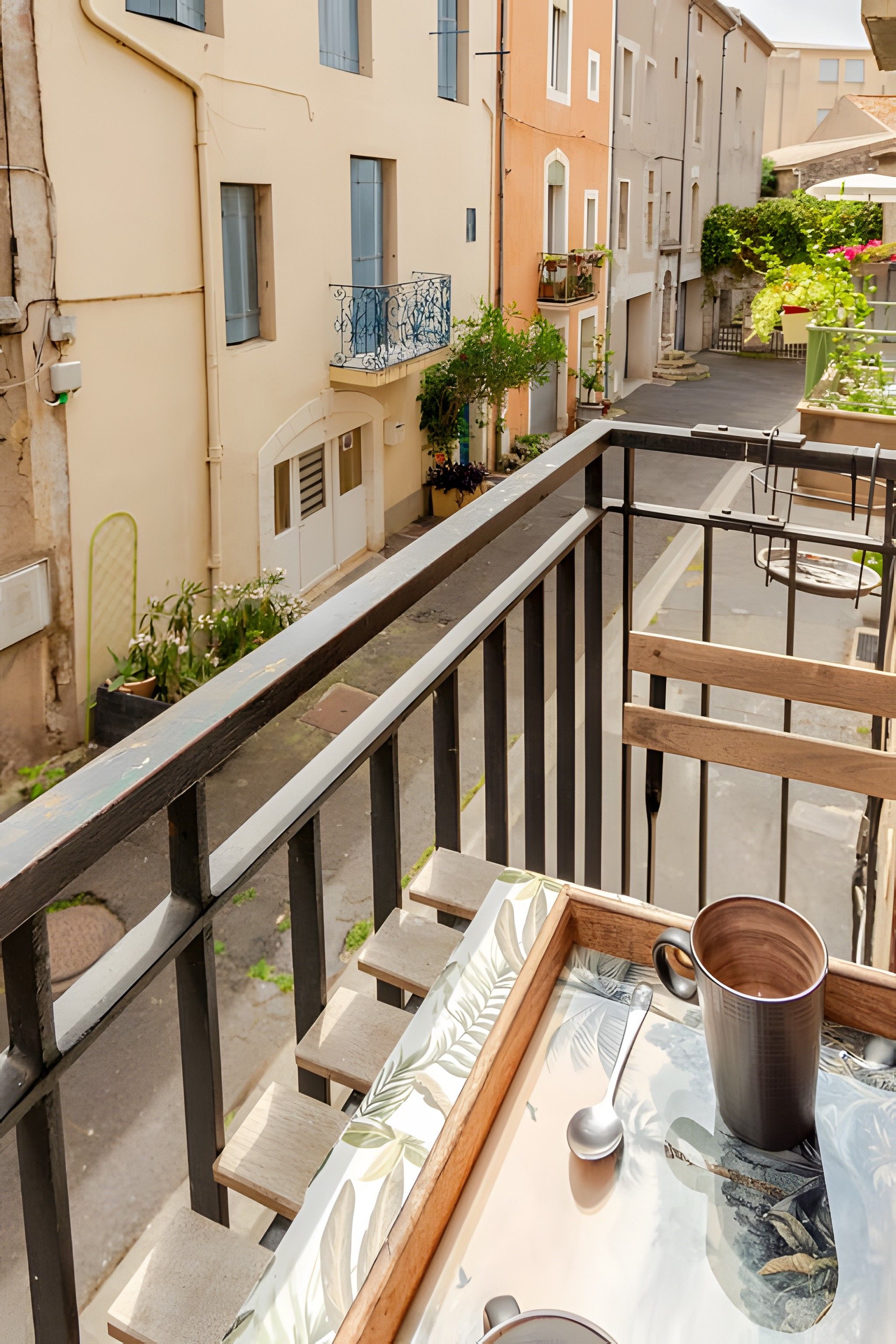A balcony with a railing, a table with a tray, a mug, and a spoon.