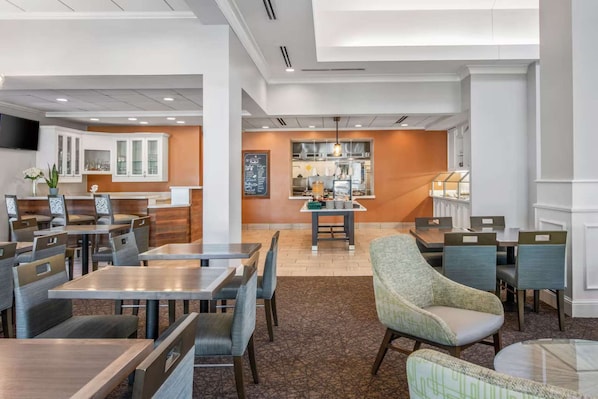 Een hotel lobby met een eetgedeelte, een receptiebalie en een keuken op de achtergrond.