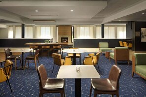 A hotel dining area with multiple tables and chairs, a bar, and a fireplace. - Minutes to Jiffy Lube Live + Bistro, Pool & Gym (Manassas)