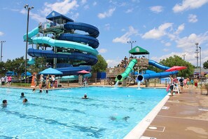 A swimming pool with multiple water slides and a lifeguard stand. - Minutes to Jiffy Lube Live + Bistro, Pool & Gym (Manassas)