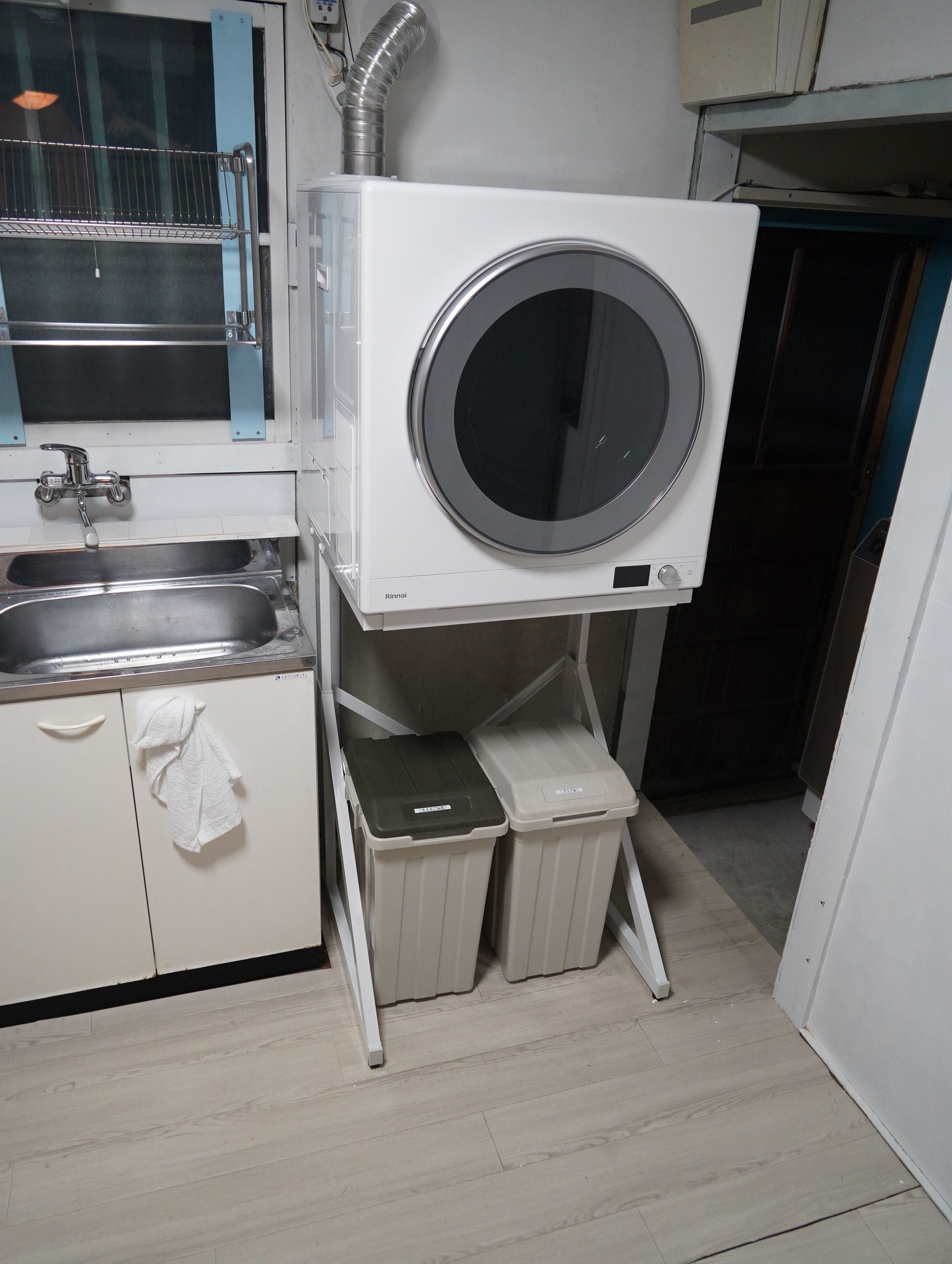 A compact kitchen with a built-in washer and dryer, a sink, and a towel rack.