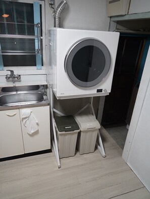 Une cuisine compacte équipée d’un lave-linge et d’un sèche-linge intégrés, d’un évier et d’un porte-serviettes.