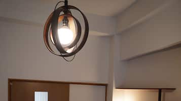 A room with a bed, a wardrobe, a wall-mounted shelf, and a circular light fixture.