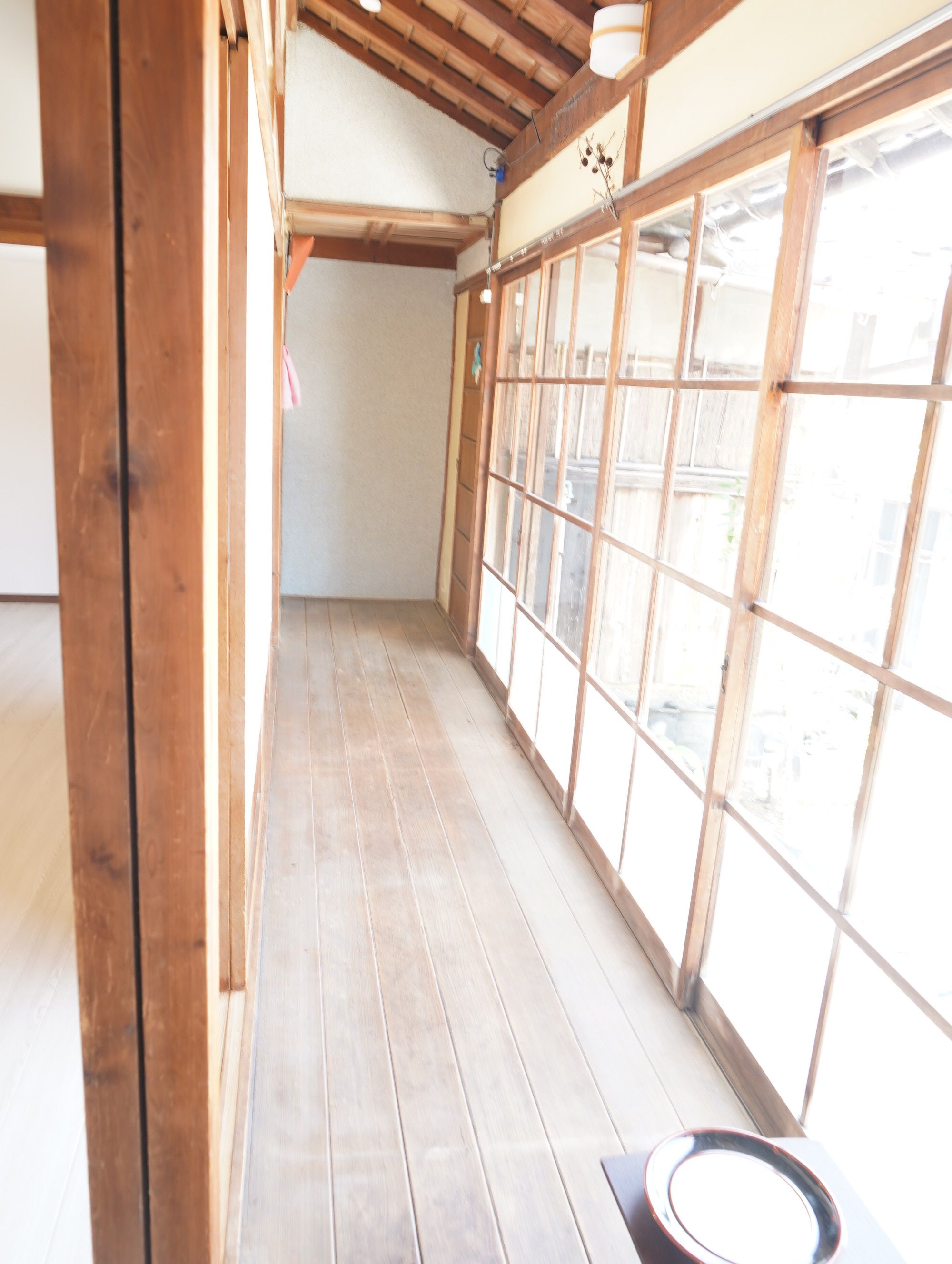 A corridor with wooden flooring and large windows.