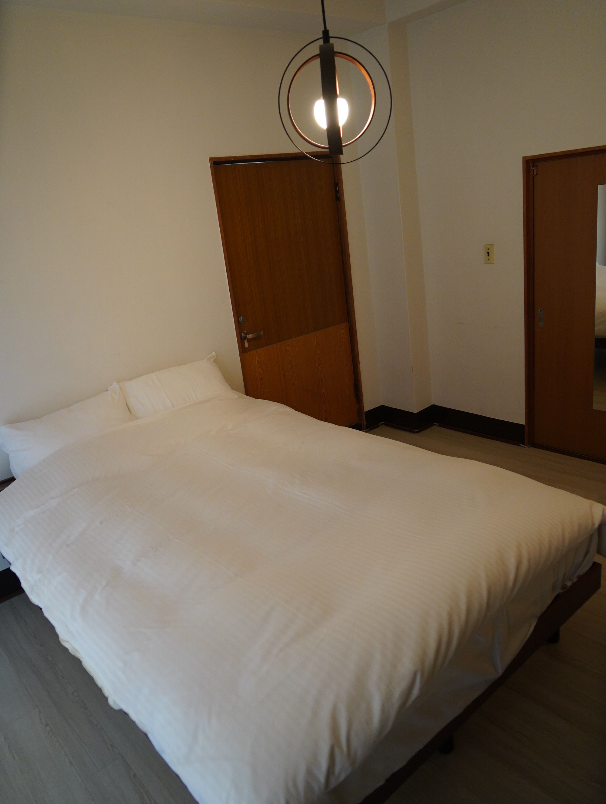 Un dormitorio con cama, armario de madera y una puerta.