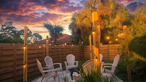 An outdoor seating area with chairs and a table, surrounded by a wooden fence and string lights. - Family Nest Pool&Gulf Coast Aventures (North Port)