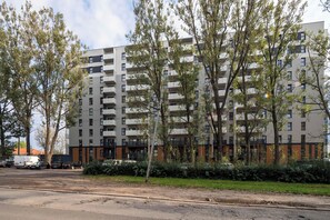 A multi-story residential building with balconies, surrounded by trees and a parking area. - Łódź | Srebrzyńska 12 | Modern Apartment | Air conditioning | Parking (Łódź)