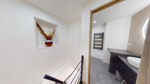 Une salle de bain moderne avec un mur blanc, un porte-serviettes noir et un lavabo blanc.