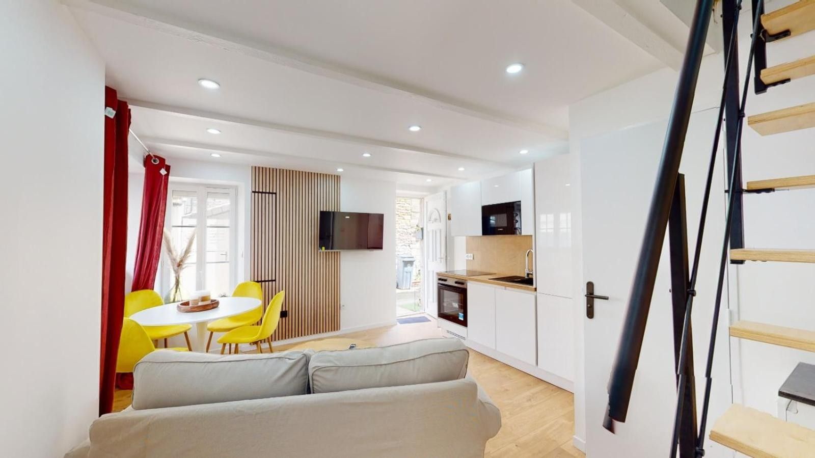 Ein modernes Interieur mit einer Couch, einem Esstisch, Stühlen, einer Küchenzeile und einer Treppe.
