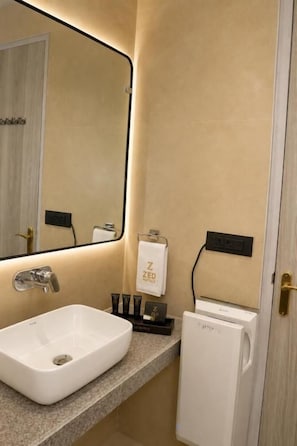 A bathroom with a white sink, a mirror, a towel rack with a towel, and a small white cabinet. - The Zed Horizon (new delhi)