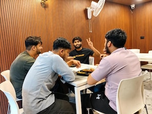 A group of people seated at a table in a room with wooden paneling and white chairs. - The Zed Horizon (new delhi)