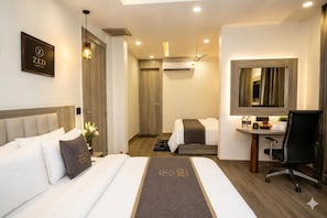 A hotel room with a bed, a desk, a chair, a mirror, and an air conditioning unit. - The Zed Horizon (new delhi)