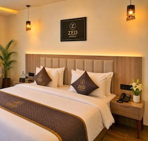 A hotel room with a bed, bedside tables, a nightstand, a lamp, and a framed sign on the wall. - The Zed Horizon (new delhi)