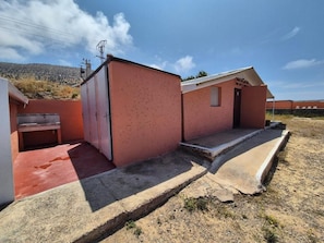 Ein Wohnhaus mit roter Fassade, einer kleinen Veranda und einem Betonweg, der zum Eingang führt.