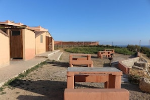 Ein Gebäude mit einer Tür und Stufen, die zu einer Terrasse mit Sitzgelegenheiten im Freien führen.