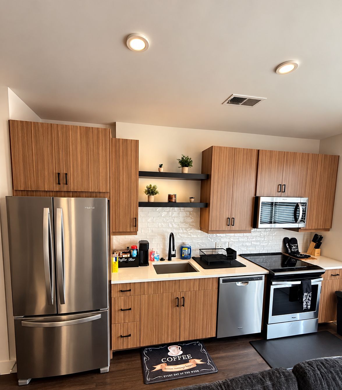 A modern kitchen with stainless steel appliances, wooden cabinets, and a built-in microwave.
