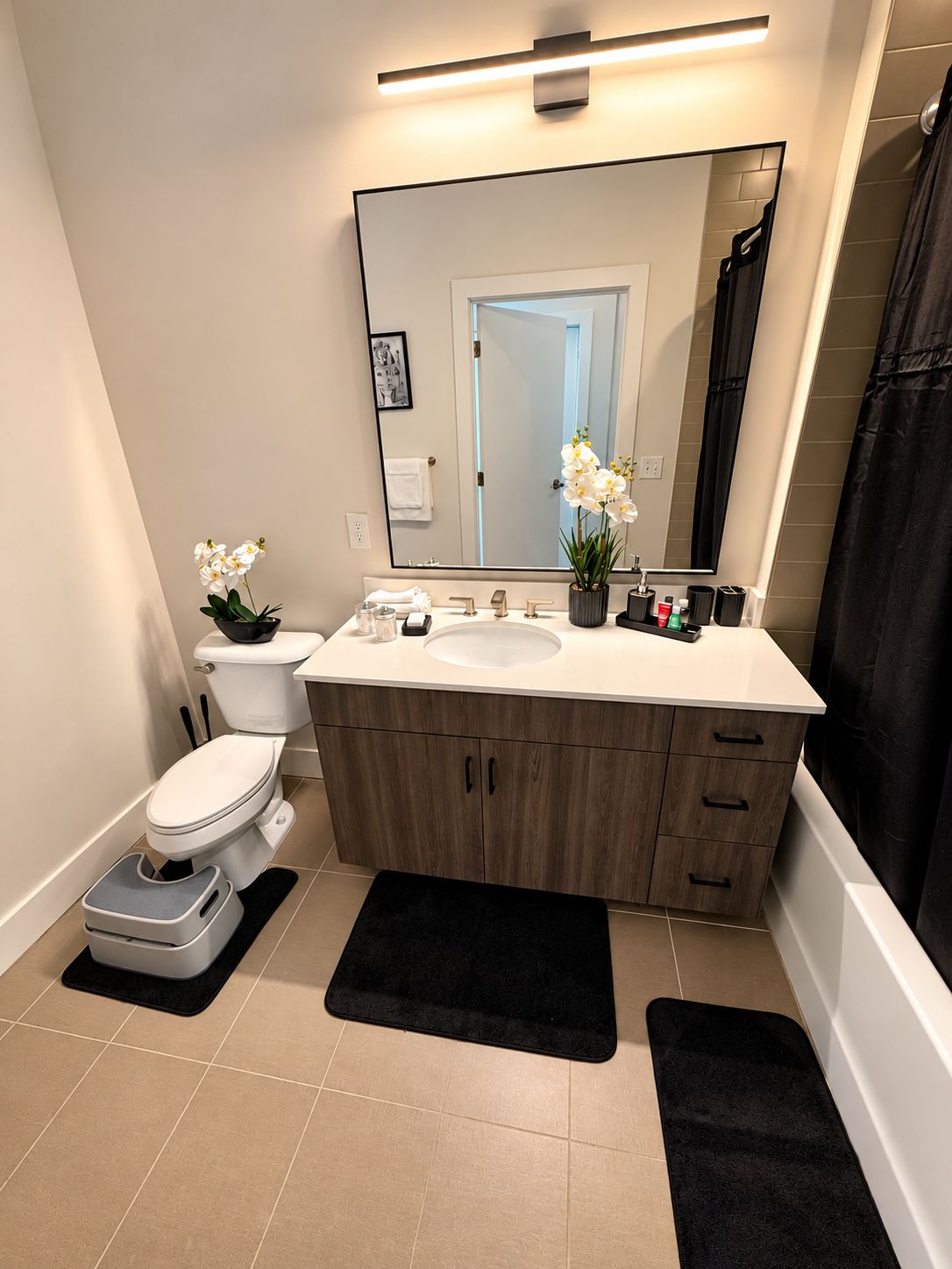 A modern bathroom with a toilet, sink, and mirror.