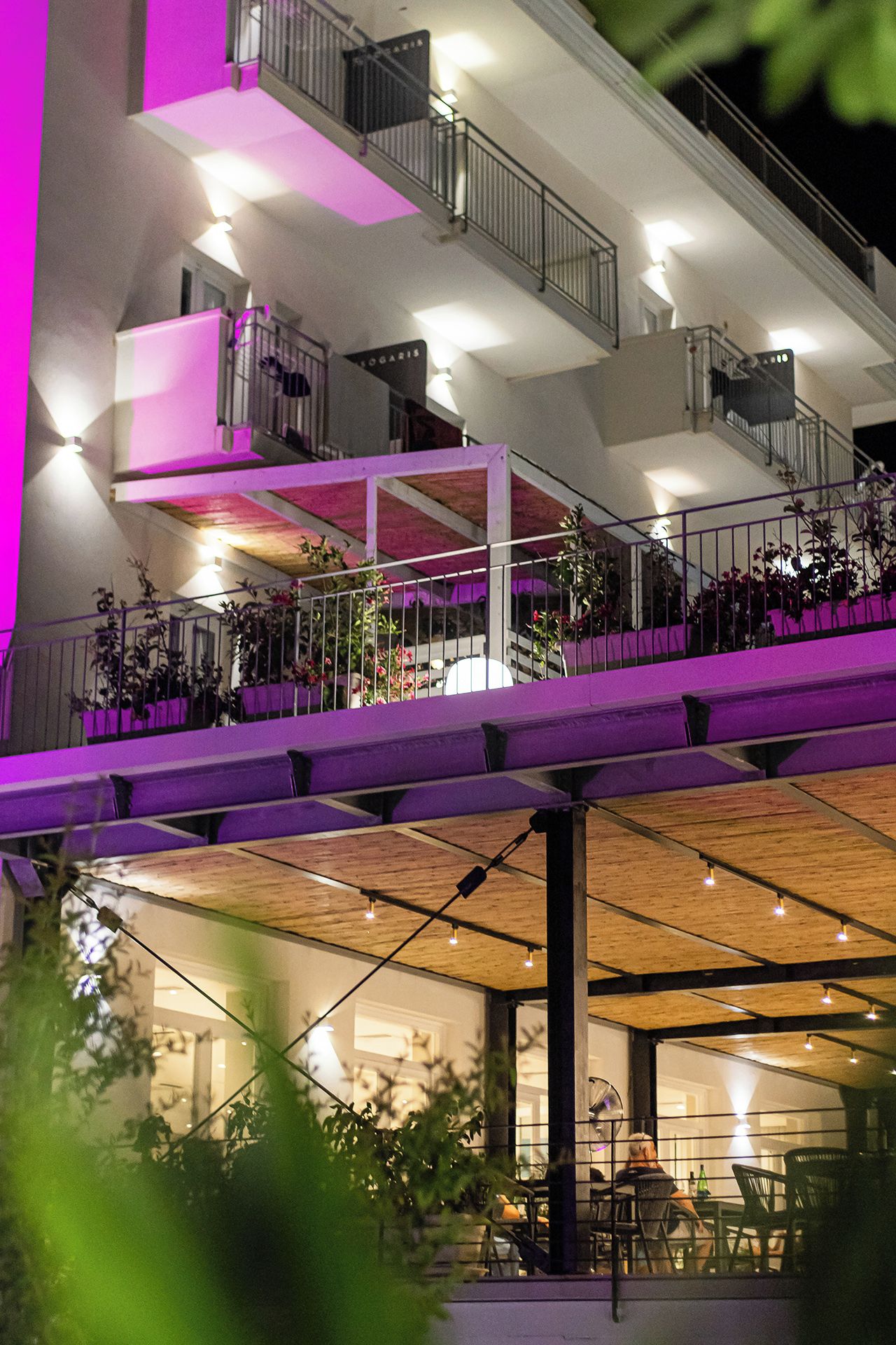 A multi-level building with outdoor seating areas, railings, and potted plants.