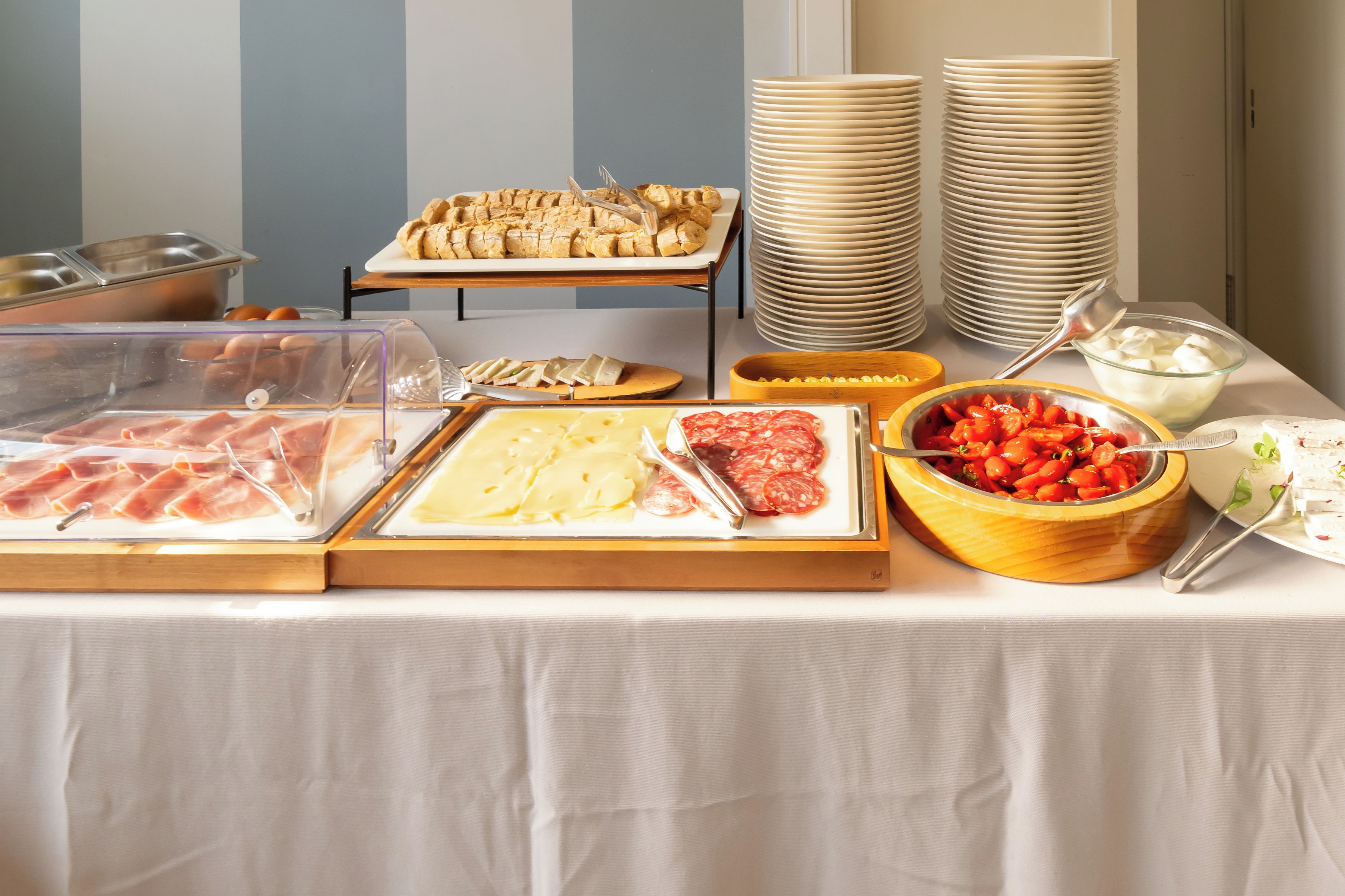 A buffet table with various food items including meats, cheeses, and vegetables.