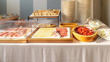 A buffet table with various food items including meats, cheeses, and vegetables.