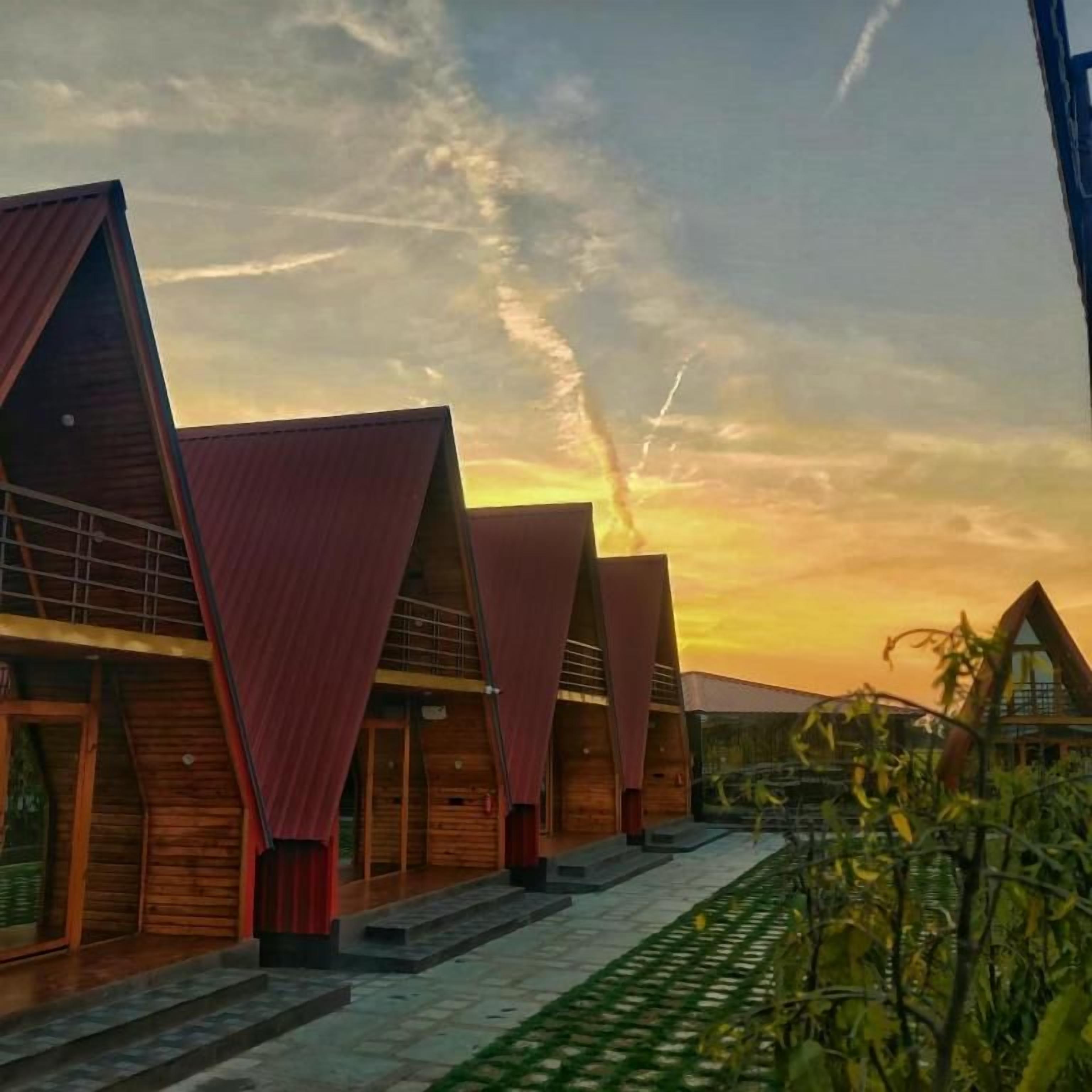 A row of modern, triangular-roofed buildings with a paved walkway in between.