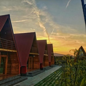 A row of modern, triangular-roofed buildings with a paved walkway in between. - Sapling's N Eyrie's Farm (Bhopal)
