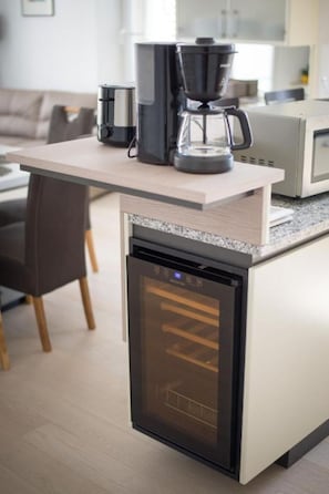 Ett kompakt kök med en inbyggd diskmaskin, en kaffebryggare och en mikrovågsugn placerad på bänkskivan.