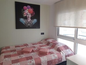 Un dormitorio con cama, ventana con persianas y un cuadro en la pared.