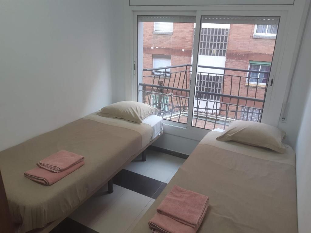 Una habitación con dos camas individuales, cada una con una almohada y una toalla doblada.