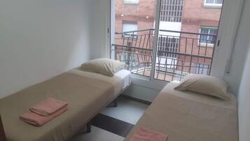 Una habitación con dos camas individuales, cada una con una almohada y una toalla doblada.
