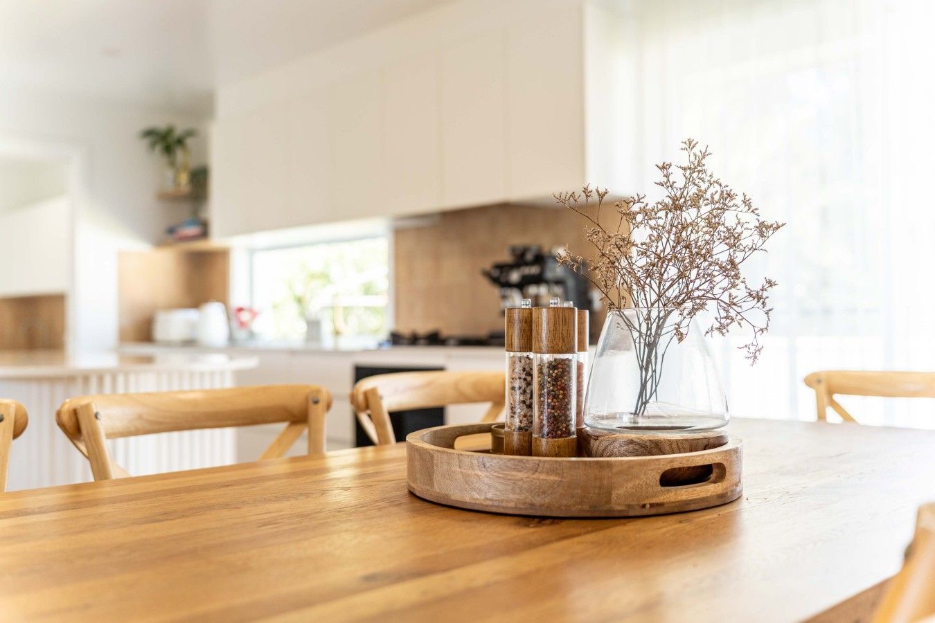 Ein Holztisch mit einer Glasvase, die getrocknete Blumen enthält, und einem Holzregal für Gewürze.