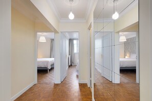 Een gang met een spiegelkast, een bed en een plafondlamp.