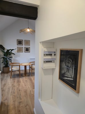 Ein Flur mit Holzboden, einem Blumentopf, einem Tisch mit Stühlen und gerahmten Kunstwerken an der Wand.