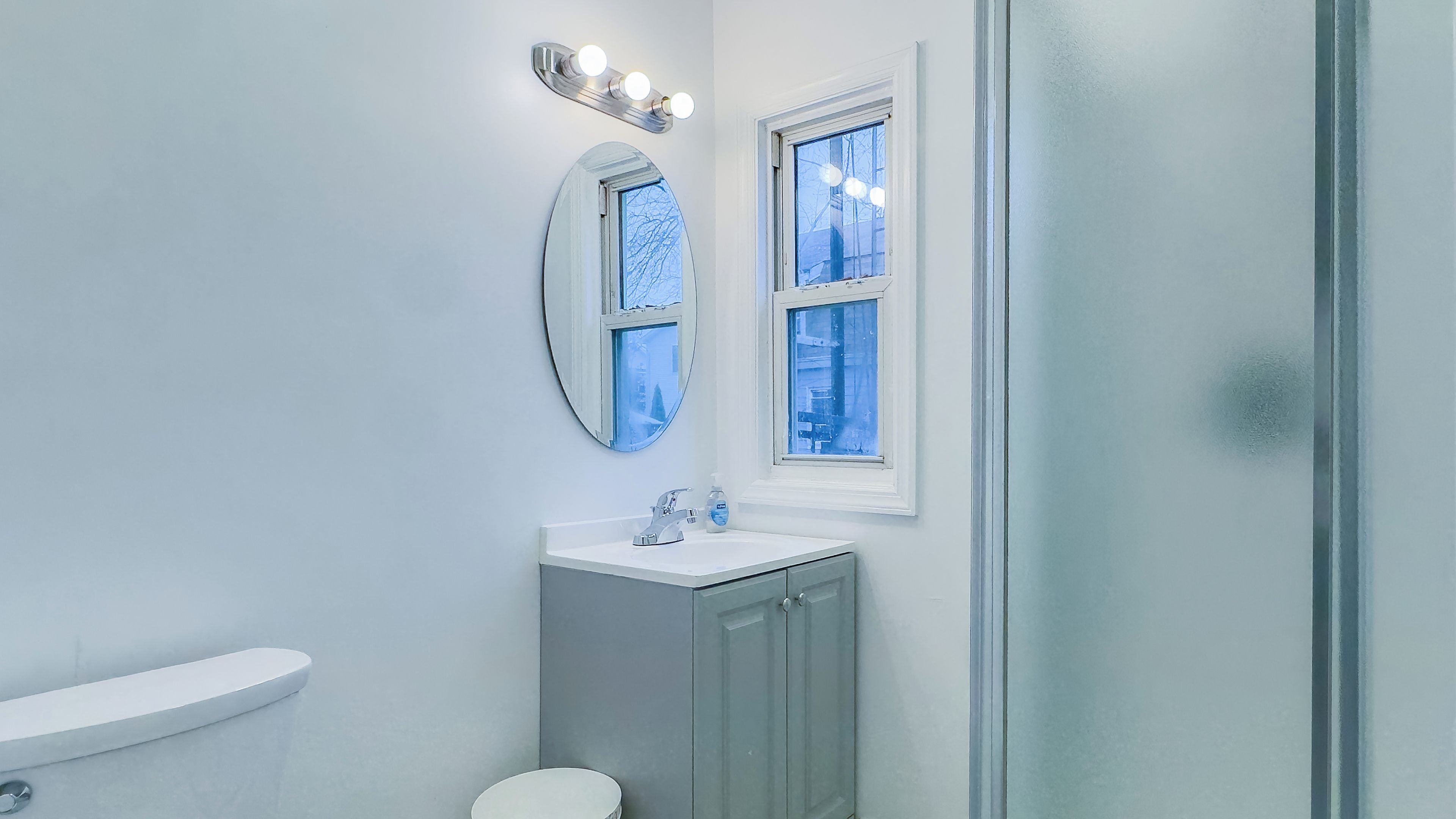 Een badkamer met toilet, wastafel en spiegel.