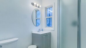 A bathroom with a toilet, a sink, and a mirror. - Chic Boutique! 3BR/1BA, 8 Ppl, 5 Beds-1 King, Street Park, Walk 2 Train, NYC 30 (West Orange)