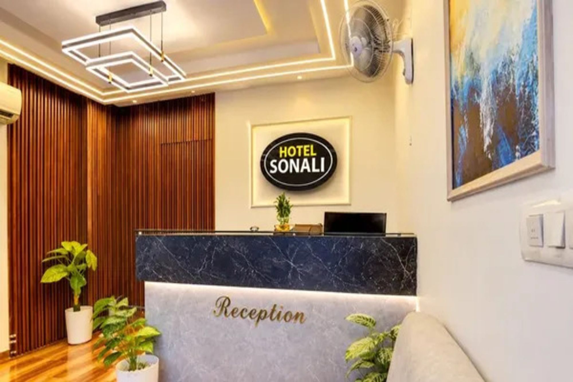 A hotel reception area with a reception desk labeled 'Reception' and a sign above it that reads 'HOTEL SONALI.'