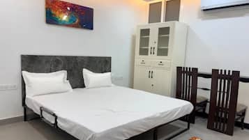 Une chambre à coucher comprenant un lit, une armoire, un bureau avec une chaise et un appareil de climatisation.