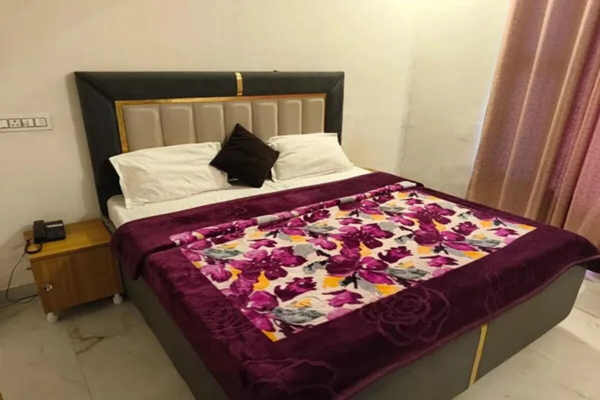 Una cama con cabecera, una mesita de noche y una colcha estampada con motivos florales.