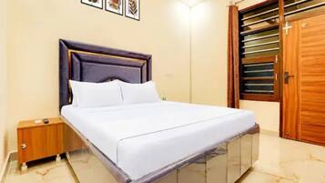 Un dormitorio con cama, mesita de noche, armario de madera, una puerta con ventana y cuadros en la pared.