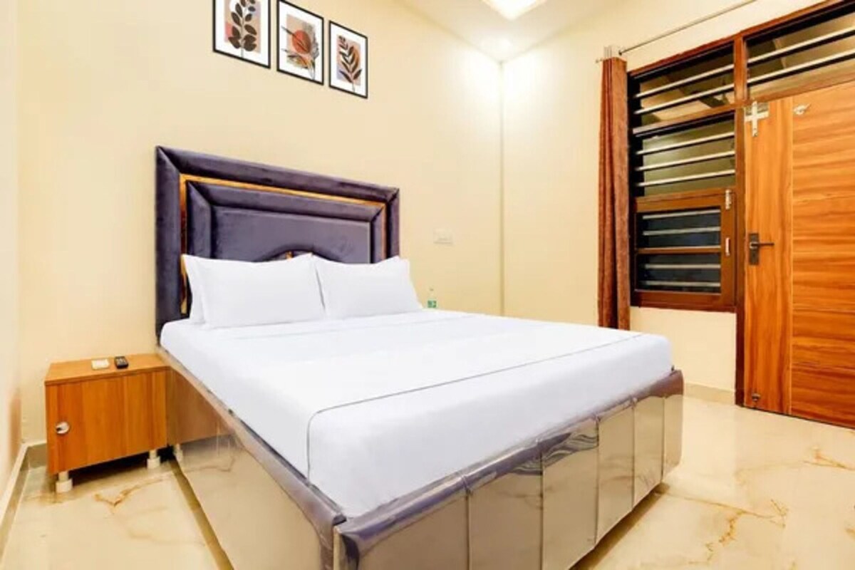 Un dormitorio con cama, mesita de noche, armario de madera y una puerta con ventana.
