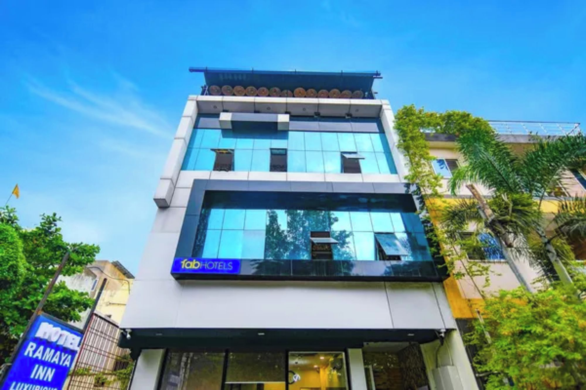 Un edificio moderno de hotel con fachada de vidrio, un cartel que dice 'Tab Hotels' y una entrada visible.