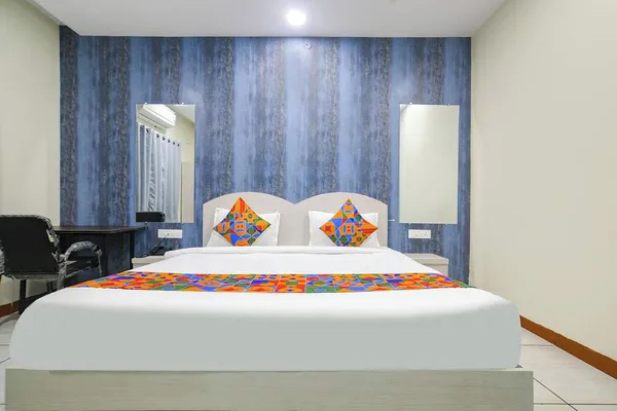 Una habitación de hotel con una cama grande, dos almohadas, un escritorio y una silla.